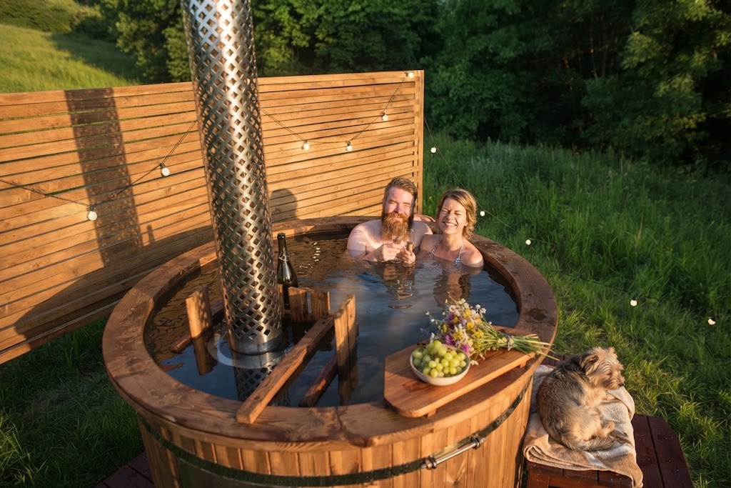 Interior of an earth-sheltered glamping burrow with a made-up bed, warm lighting and a glazed front elevation