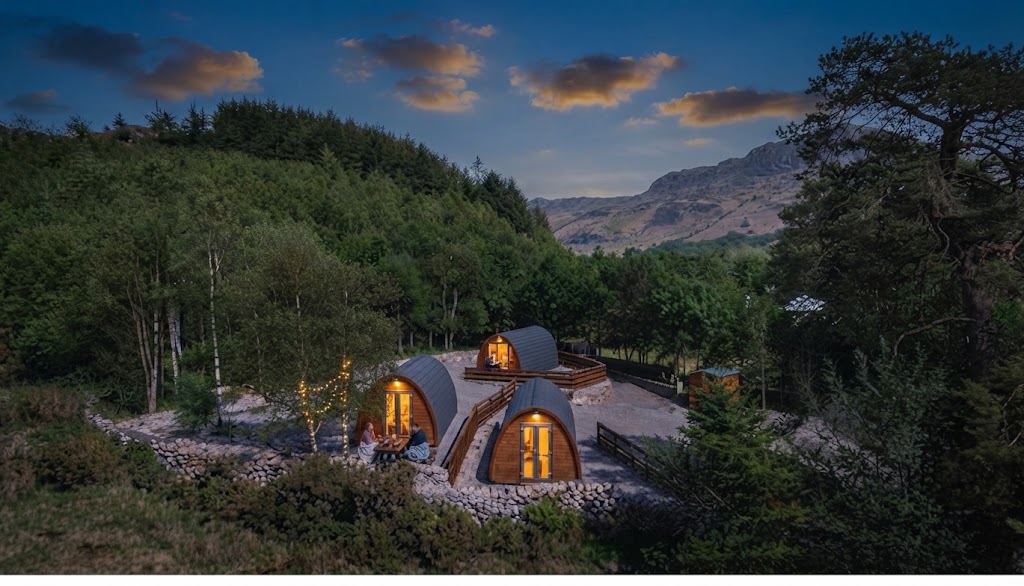 Interior of a glamping pod with a made-up double bed, folded towels, bedside lamp and rain running down the window