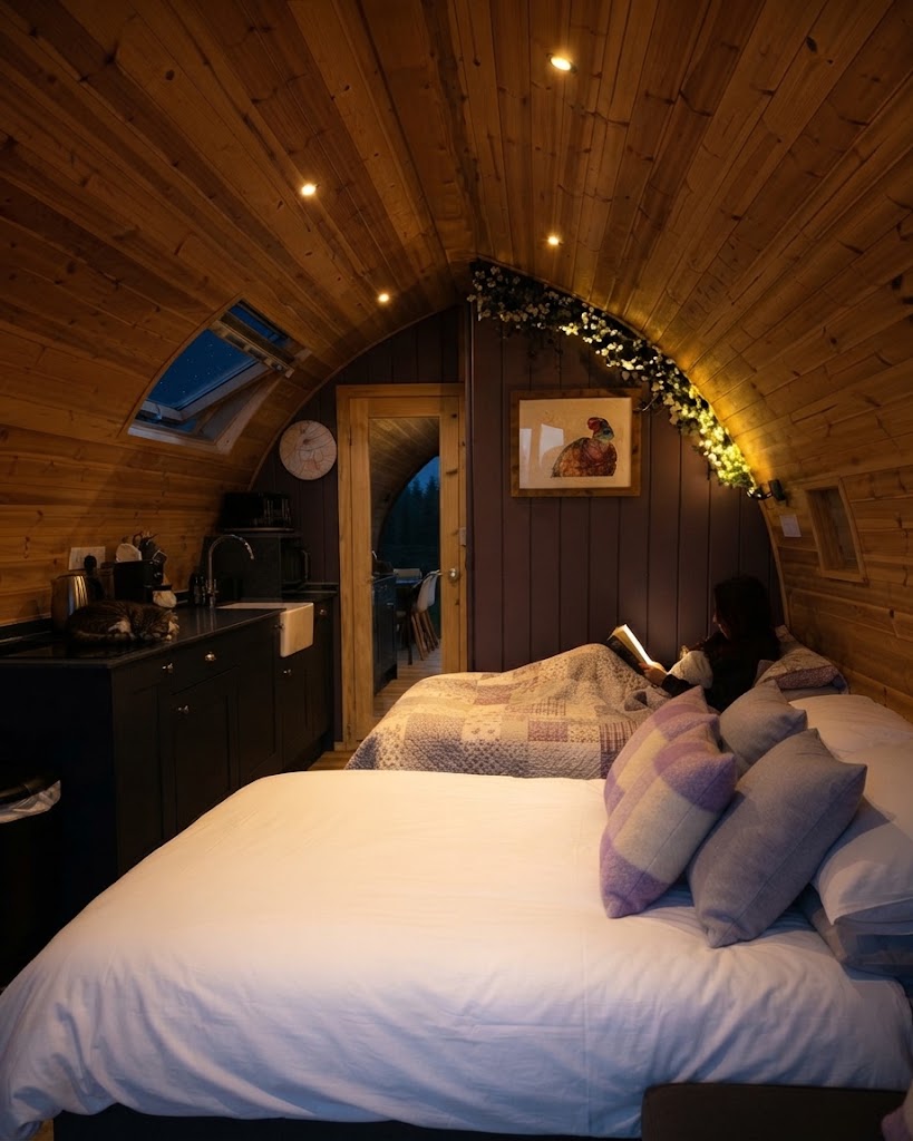 Electric hot tub with jets running and steam rising on a decked terrace outside a Lake District glamping lodge at night