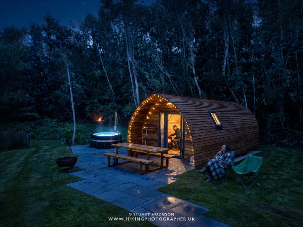Dark sky above a Lake District glamping pod with the Milky Way visible and warm light in the pod window