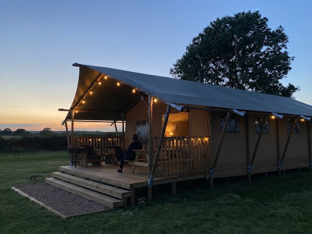 Cyclists and walkers passing a Lake District glamping pod site with bikes leaning against a fence