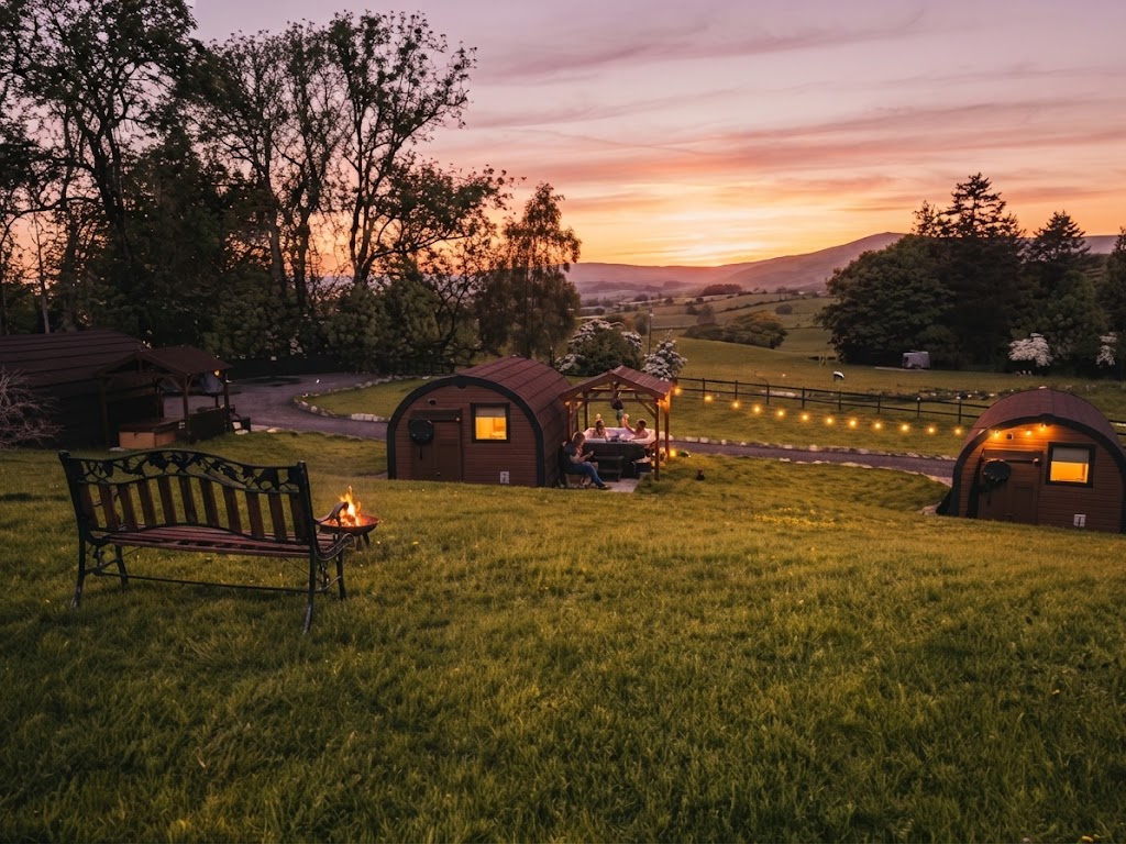 Panoramic Lake District view down a long lake with fells on both sides and glamping pods on a hillside