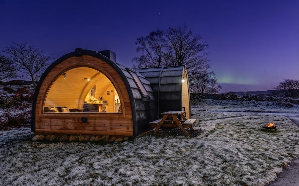 Private hot tub steaming on a decked terrace outside a luxury Lake District glamping unit at dusk with no other buildings visible