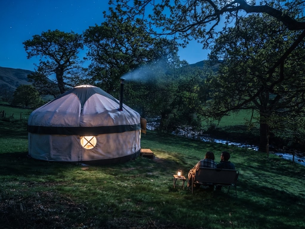 Large established campsite with rows of camping pods, a shower block building and touring caravans in the background