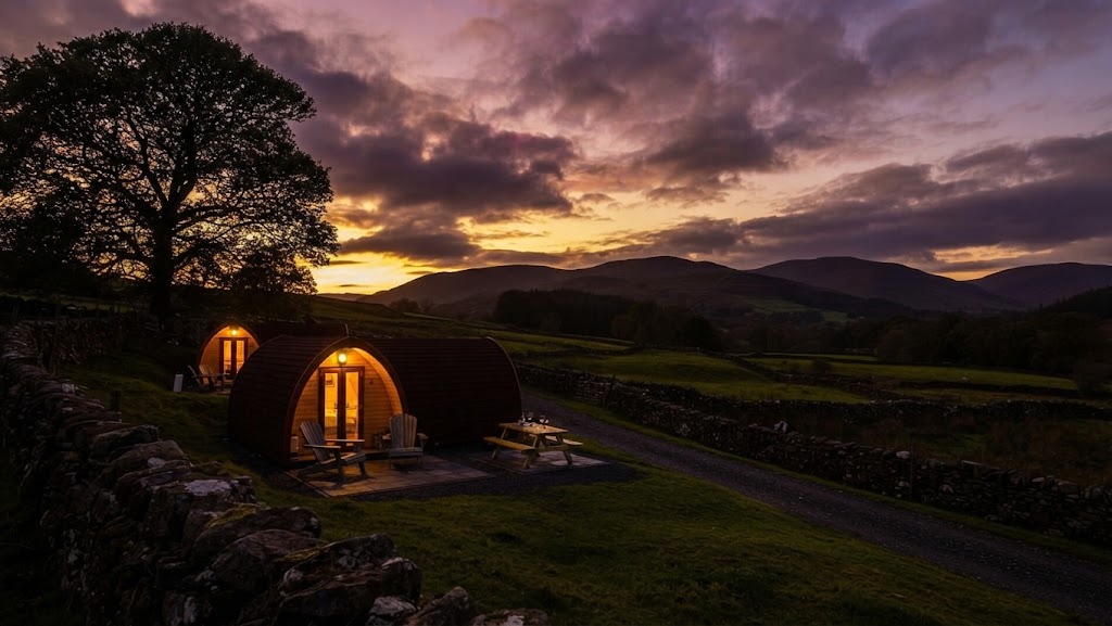 Small Lake District glamping site with two units spaced across a sloping field at golden hour