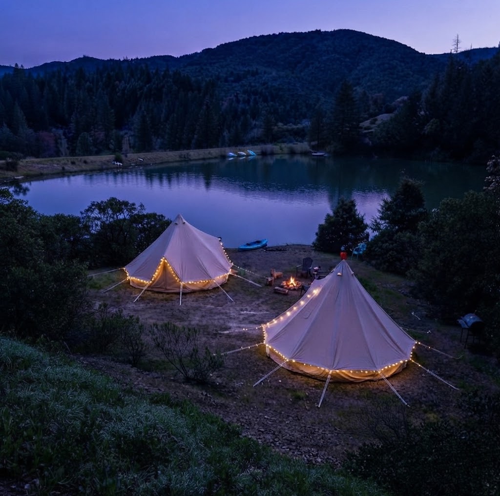 Ensuite luxury camping pod interior with a made-up king bed, kitchenette and shower room door